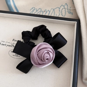 Detailed macro view of black satin scrunchie with lavender ribbon rose and bow