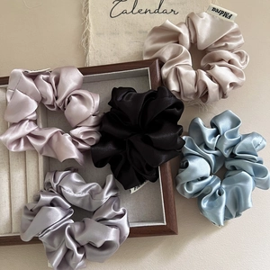 Five pieces of glossy satin scrunchies in various Morandi colors on a wooden tray