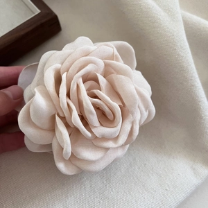Détail des pétales en tissu texturé de la pince à cheveux rose 3D de couleur beige