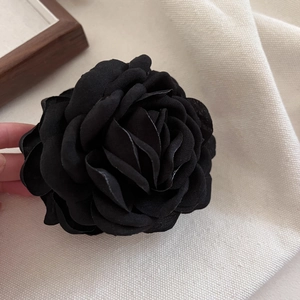 Gros plan détaillé d'une pince à cheveux rose en tissu noir sur fond en textile beige