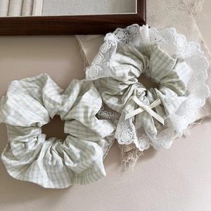 Chouchous à carreaux vert menthe avec bordure en dentelle et noeud sur plateau bois