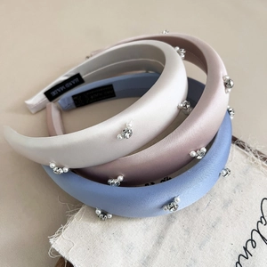 Detailed view of handmade satin headbands with faux pearls and rhinestones on soft fabric