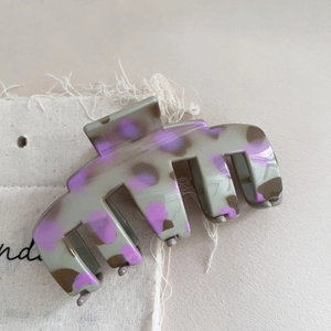 Close-up of a large leopard print hair claw clip in grey and purple acetate texture