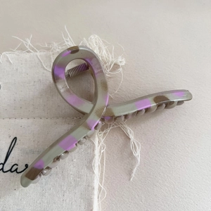 Close-up of grey and purple leopard print hair claw clip on beige linen fabric