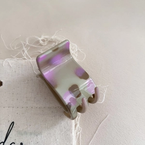 Detail of grey and purple marble pattern hair claw clip on beige canvas fabric