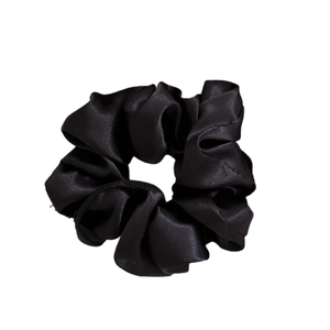 Silky black satin scrunchie for hair styling with smooth texture on white background