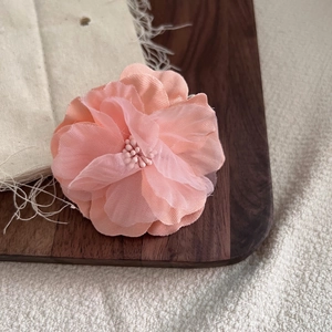 Dettaglio ravvicinato di una clip floreale 3D in tessuto rosa fatta a mano su legno