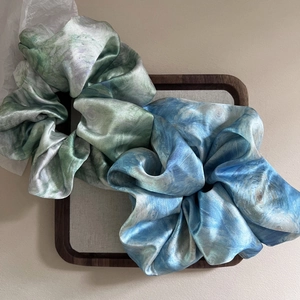 Elegant satin hair scrunchies with blue and purple ink marble pattern in a wooden tray