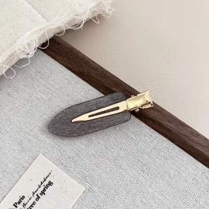 Detail of dark grey matte acetate hair clip with golden metal duckbill clamp