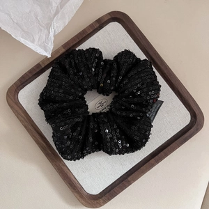 Close-up of black sequined hair scrunchie made of 70% polyester and 30% cotton in a tray