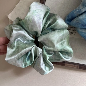 Elegant satin hair scrunchie with blue and purple watercolor marble print on wooden tray