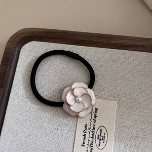 Elegant camellia hair tie with white flower, gold trim and pearl on elastic black band