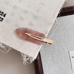 Elegant acetate hair clip with pink marble pattern and gold glitter on linen fabric
