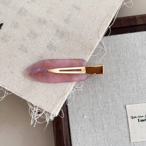 Close-up of pink marble acetate hair clip with gold glitter on a rustic linen background