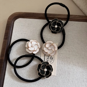 Detail of elegant camellia hair ties with pearls on wooden tray with grey liner