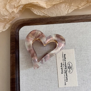 Close-up of heart-shaped marble acetate hair claw clip with pink and cream textures