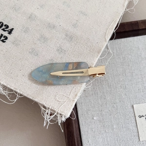 Macro shot of marble texture resin hair clip with gold glitter and metal duckbill clip