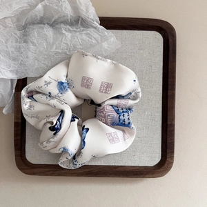 Detailed macro view of a silk hair scrunchie with blue ink landscape patterns