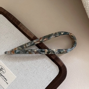 Detailansicht der U-förmigen Haarnadel mit elegantem grau-braunem Marmormuster auf Tablett