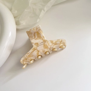 Detailed macro shot of a cream marbled acetate hair claw with Barrette la France logo