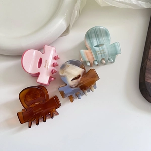 Set of four elegant acetate hair claws in pink, marble green, amber, and mixed tones