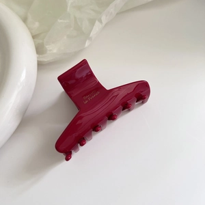 Macro shot of a dark red acetate hair claw clip with golden Barrette la France lettering