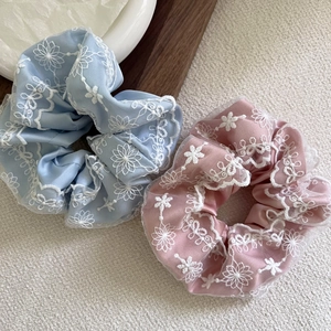 Détail de chouchous en satin bleu clair et rose avec broderie marguerite en dentelle blanche