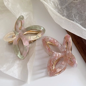 Detailed macro view of two hollow butterfly hair claws with acetate marble textures