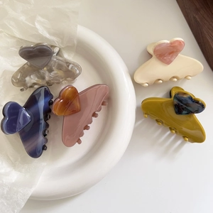 Elegant heart-shaped acetate hair claws in various colors on a white ceramic plate