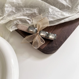 Détail d'une pince à cheveux en tulle champagne ornée de strass gris et métal doré
