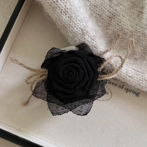 Pince à cheveux rose en tissu noir avec nœud en toile de jute sur support minimaliste