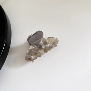 Minimalist marble pattern hair claw clip with a grey heart decoration on white background