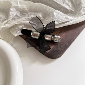 Détail de la pince à cheveux nœud en tulle noir avec trois strass rectangulaires