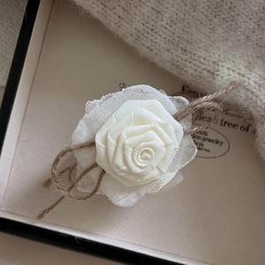 Détail d'une pince à cheveux rose en résille crème avec un nœud en ficelle rustique