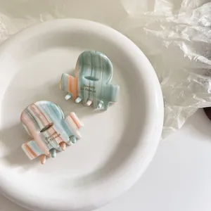 Detail of acetate hair clips with blue and pink marble patterns in a white ceramic dish