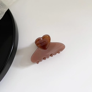 Detail view of heart-shaped hair claw with amber tortoiseshell and dusty pink textures