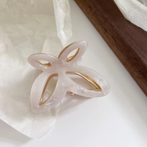 Detail of elegant butterfly claw clip with pearlescent acetate and gold metal support