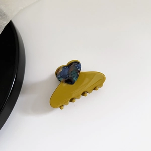 Detail view of mustard yellow acetate heart claw clip with marble blue heart accent