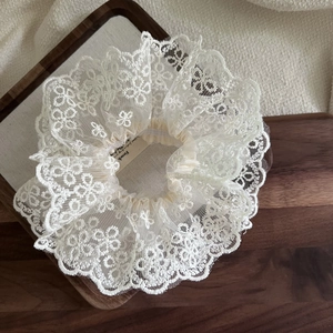 Elegant beige floral lace scrunchie with French label on premium wood tray setting