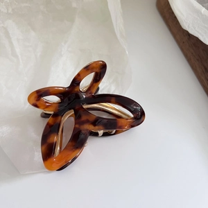 Detail view of butterfly acetate hair claw clip with shell pattern and gold metal spring