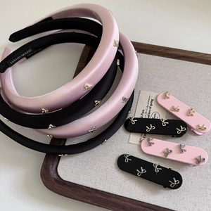 Dettaglio ravvicinato di cerchietti in raso rosa e nero con eleganti fiocchi metallici