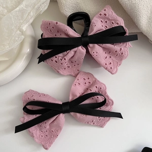 Detailed close-up of pink lace embroidery bow hair clips with delicate black silk ribbon