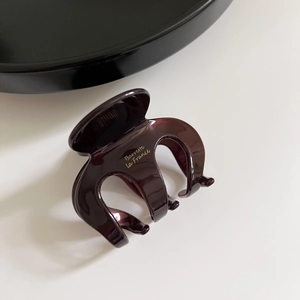 Detail of a dark amber acetate octopus hair claw clip with golden Barrette La France text