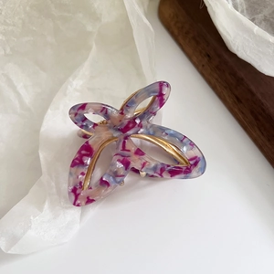 Macro view of butterfly hair claw clip with colorful marbled acetate and gold metal spring