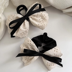 Detail view of white lace bow hair clip and scrunchie with elegant black ribbon accents