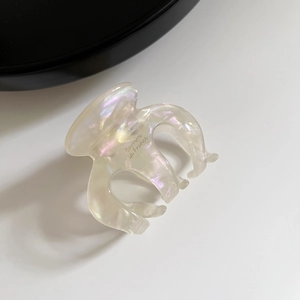 Macro shot of iridescent white acetate hair claw with golden Barrette La France text detail