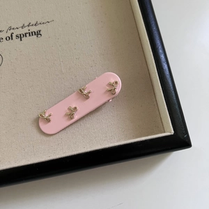 Fermaglio per capelli rosa rettangolare con fiocchi dorati su vassoio espositivo
