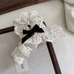Elegant beige floral lace hair claw clip with black satin bow on linen background
