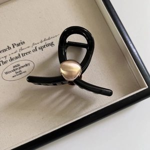 Pince à cheveux noire minimaliste avec perle or rose dans un coffret à bijoux