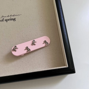 Dettaglio di un fermaglio per capelli rosa con quattro piccoli fiocchi in metallo argento